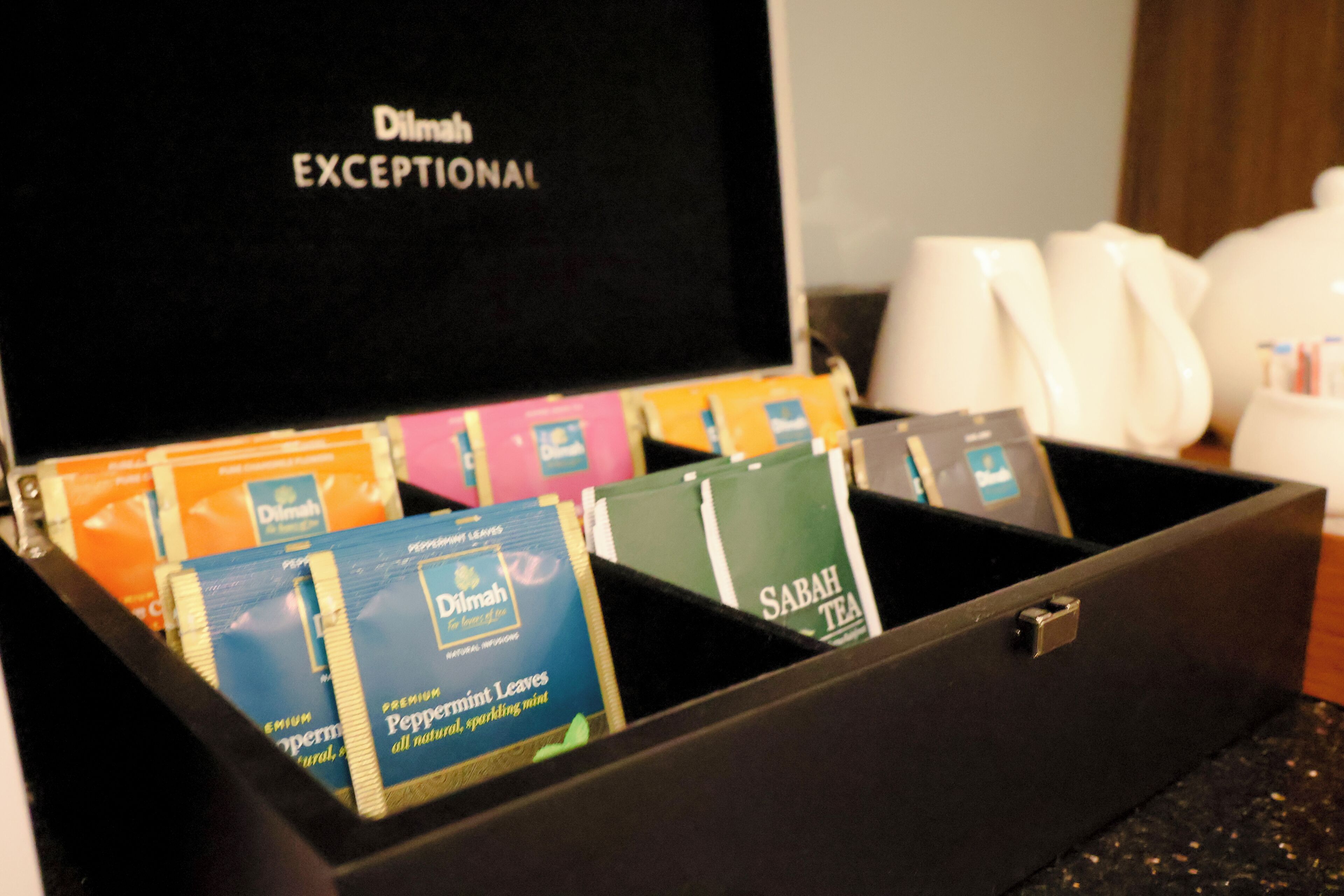 A black box with compartments containing various tea bags and a coffee maker.