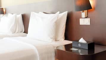 Ein Hotelzimmer mit zwei Betten, einem Nachttisch mit Lampe und einer Taschentuchbox.