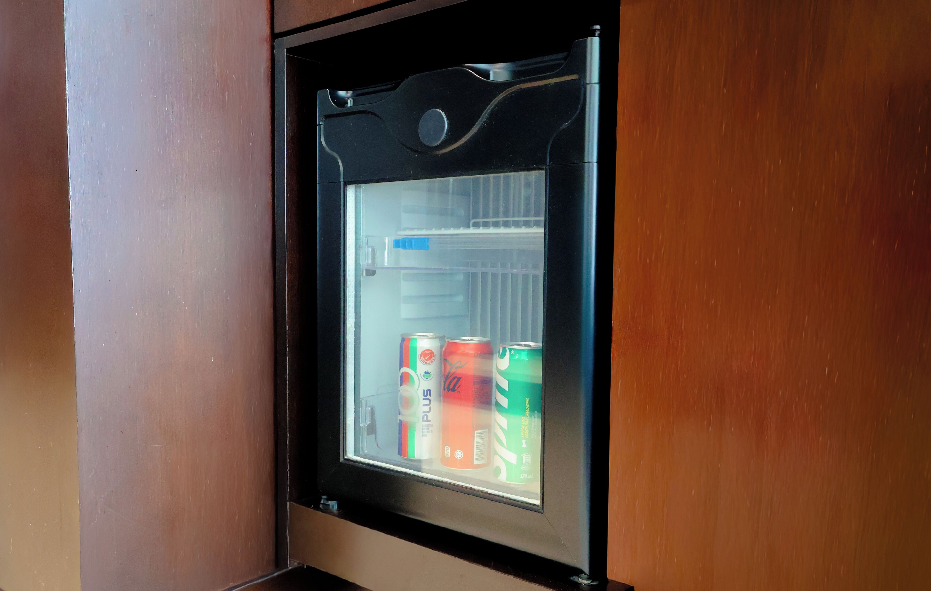 A refrigerator with a glass door, containing three beverage cans.