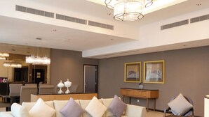 A spacious living room with a modern sofa, a round coffee table, and a chandelier. - Grandis Hotel (Kota Kinabalu)