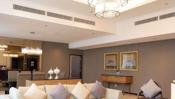 A spacious living room with a modern sofa, a round coffee table, and a chandelier. - Grandis Hotel (Kota Kinabalu)