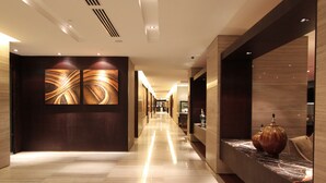 A modern hotel corridor with a marble floor, dark wooden walls, and a large abstract artwork on the left. - Grandis Hotel (Kota Kinabalu)