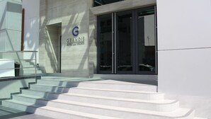A modern hotel entrance with a glass facade, a visible staircase, and a sign for 'GRANDIS HOTEL'. - Grandis Hotel (Kota Kinabalu)