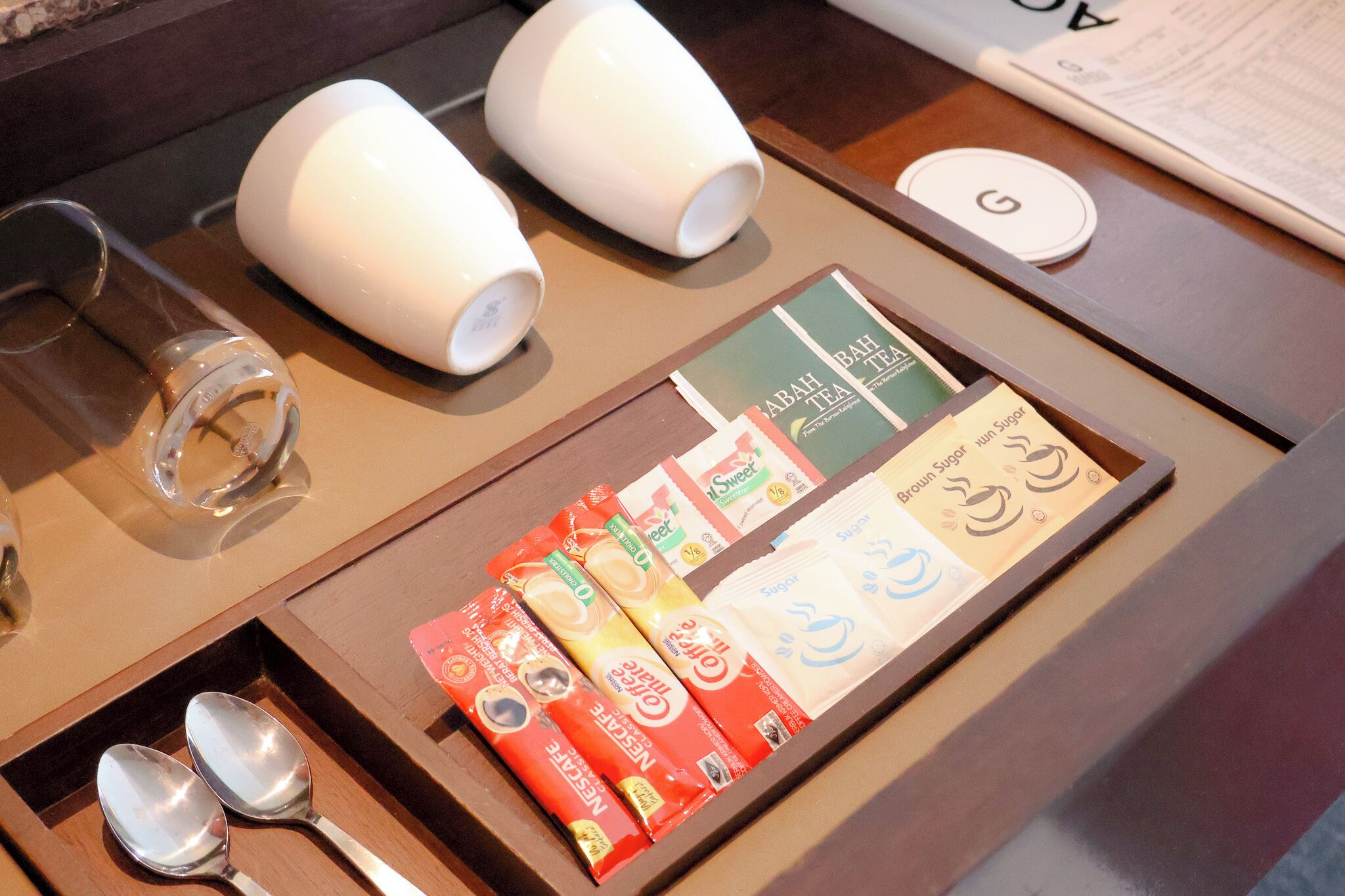 A tray with tea bags, a spoon, and a glass.