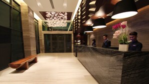 A reception area with a marble counter, wooden bench, and decorative wall panels. - Grandis Hotel (Kota Kinabalu)