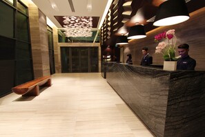 A reception area with a marble counter, wooden bench, and decorative wall panels. - Grandis Hotel (Kota Kinabalu)