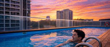 Piscina com vista para o pôr do sol, uma cadeira de piscina e um salva-vidas.