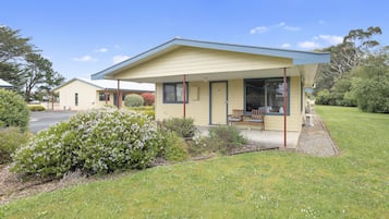 Situated in a serene garden, this charming building features a covered porch and a pathway leading to its entrance.