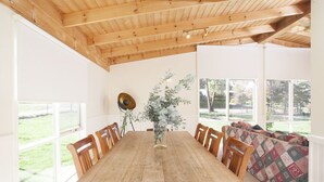 Ein Essbereich mit einem Holztisch und Stühlen, einer Blumenvase sowie Blick ins Freie.
