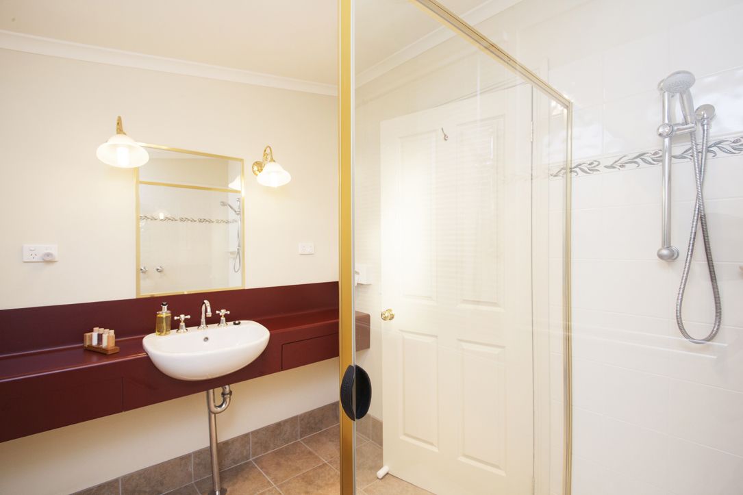 A bathroom with a white sink, a mirror with lights, and a shower with a glass door.