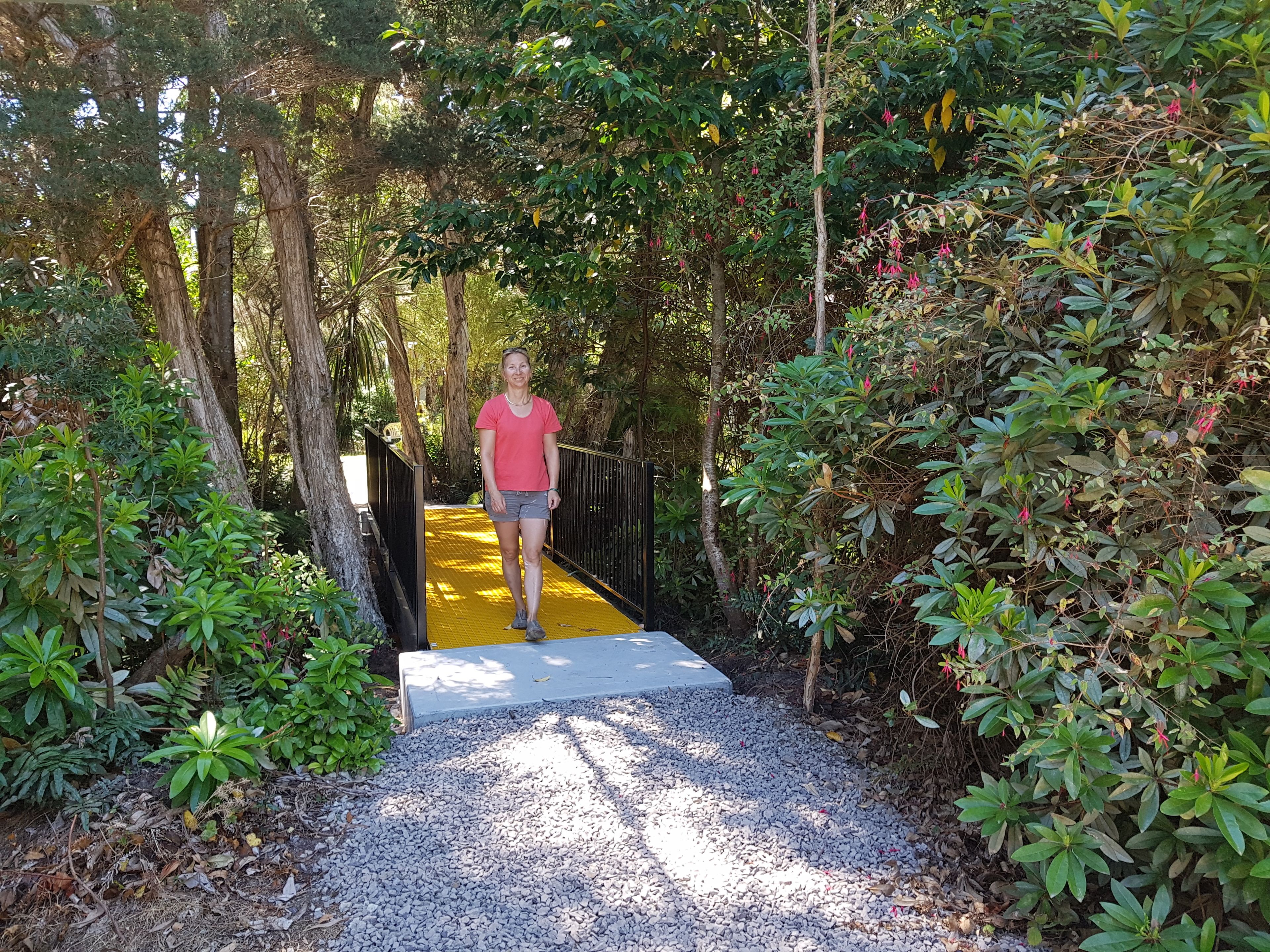 A pathway leading through a lush garden with dense foliage and trees.