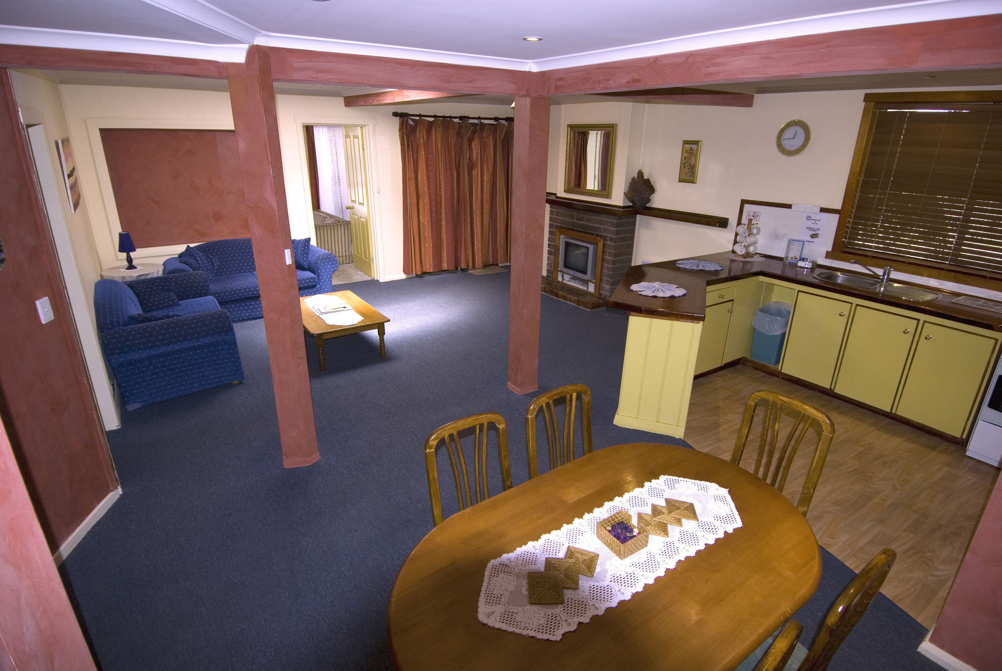 Una sala de estar con un sofá, una mesa de comedor con sillas, una zona de cocina y una chimenea.