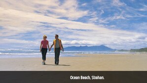 Escena de playa con dos personas caminando, y se lee el texto 'Ocean Beach, Strahan'.