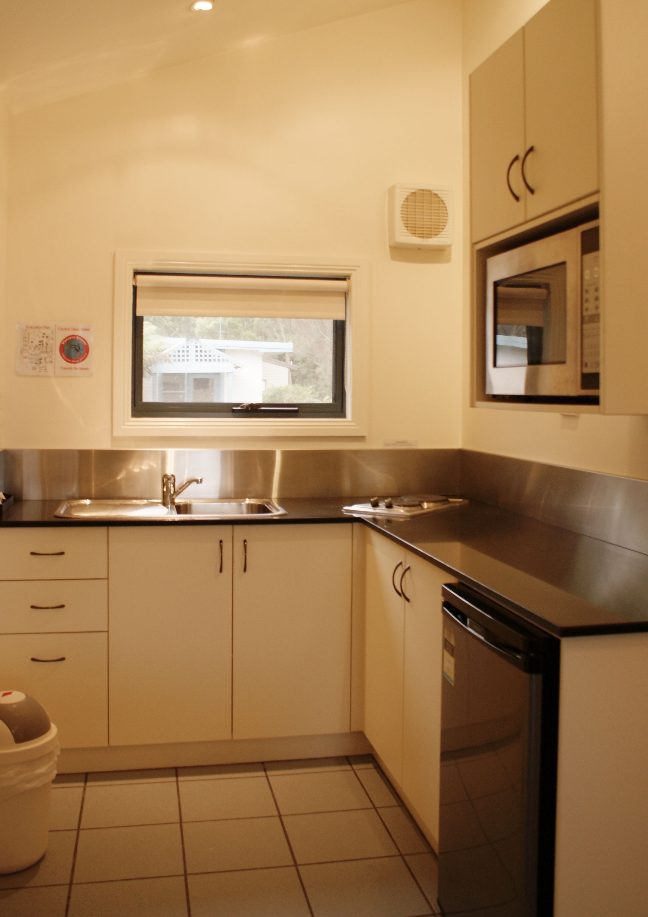 Una cocina compacta con un fregadero, estufa, microondas y armarios.