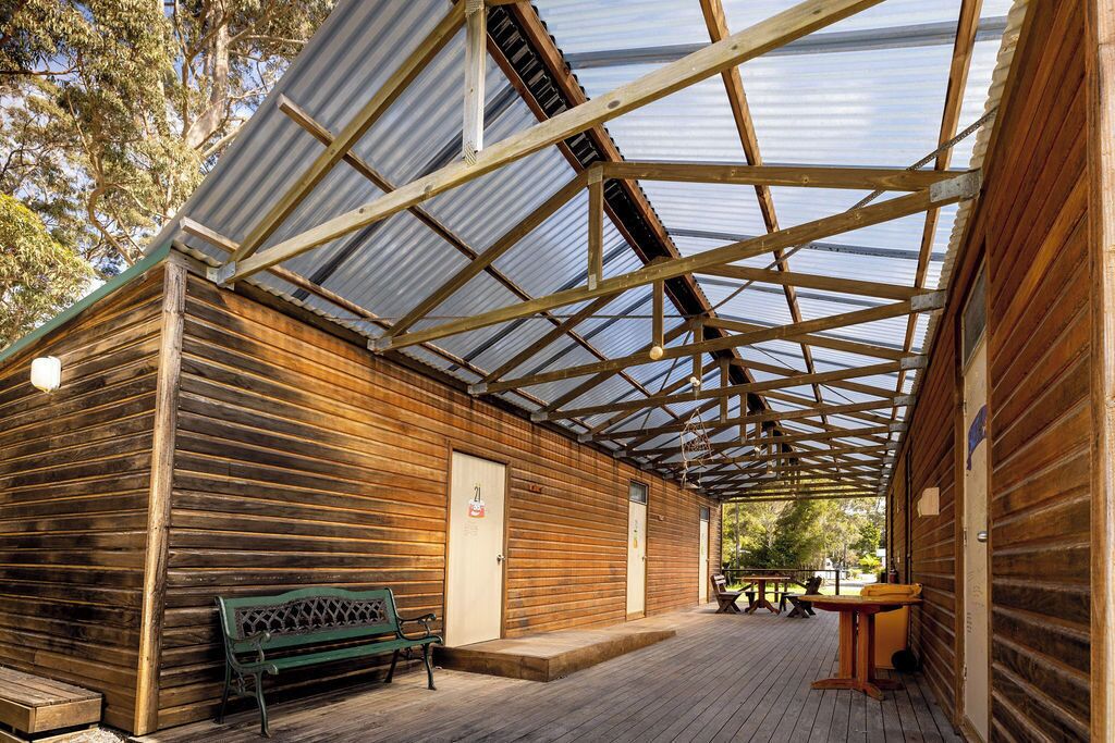 A wooden cabin with a covered porch, a bench, and a table.