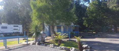 A small building with a blue roof, surrounded by a gravel area with rocks and small plants.