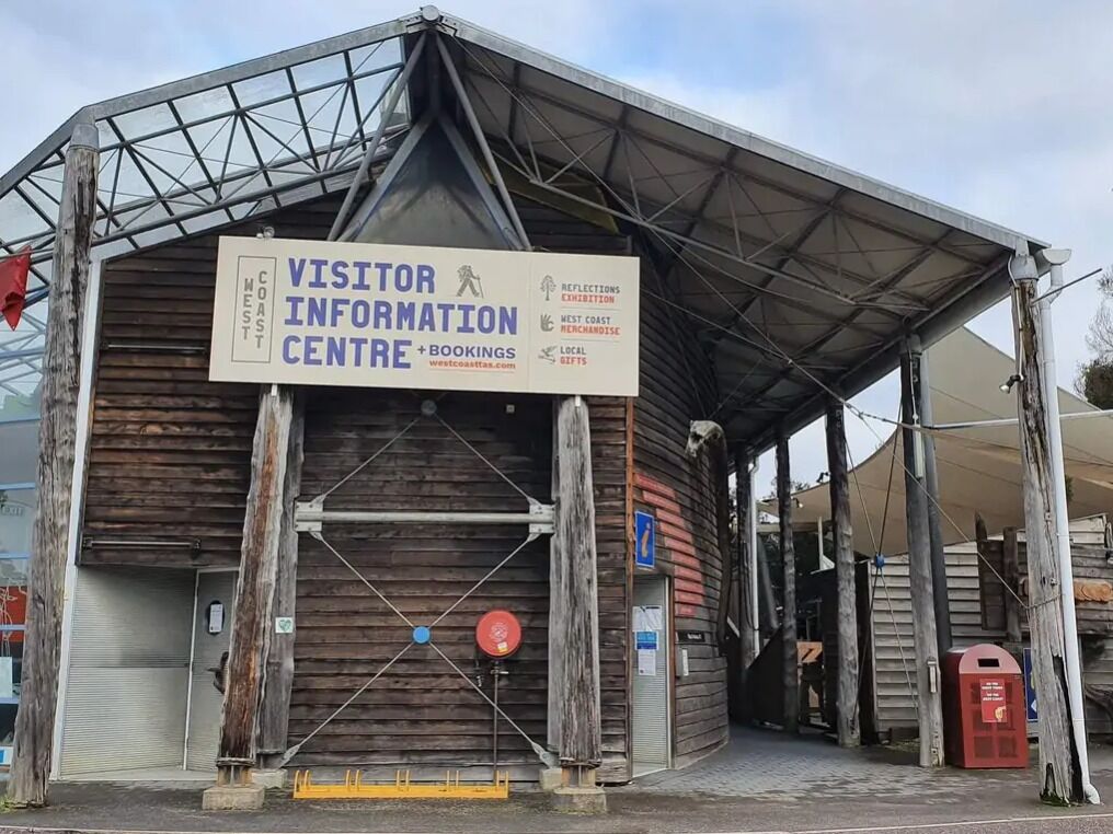 A visitor information center with a signboard, wooden exterior, and a covered entrance.