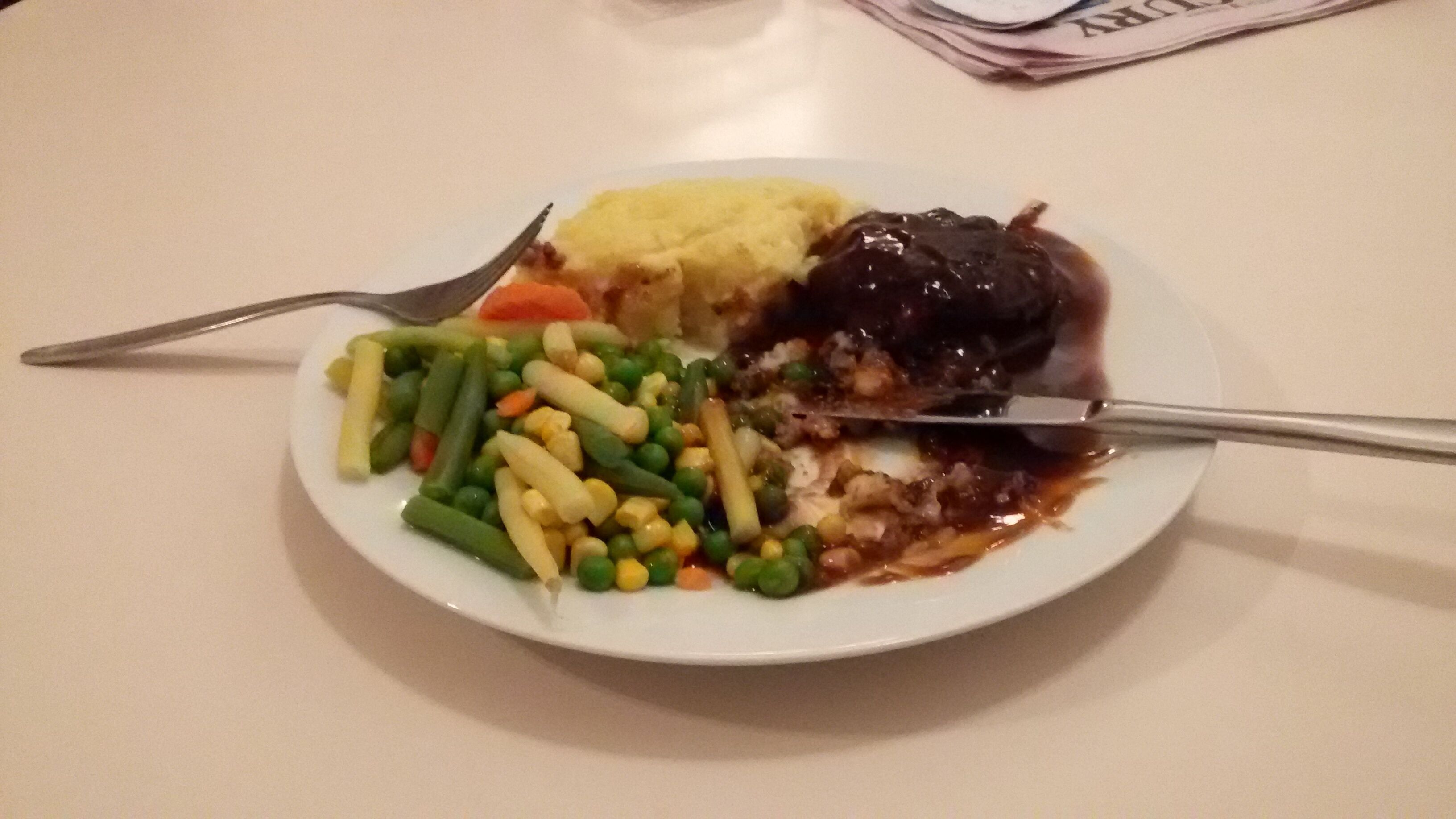 A plate with various vegetables and a piece of meat, possibly a steak, on a white plate.
