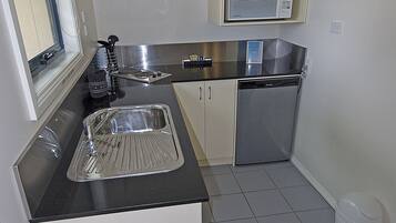 A compact kitchen with a sink, microwave, and dishwasher.