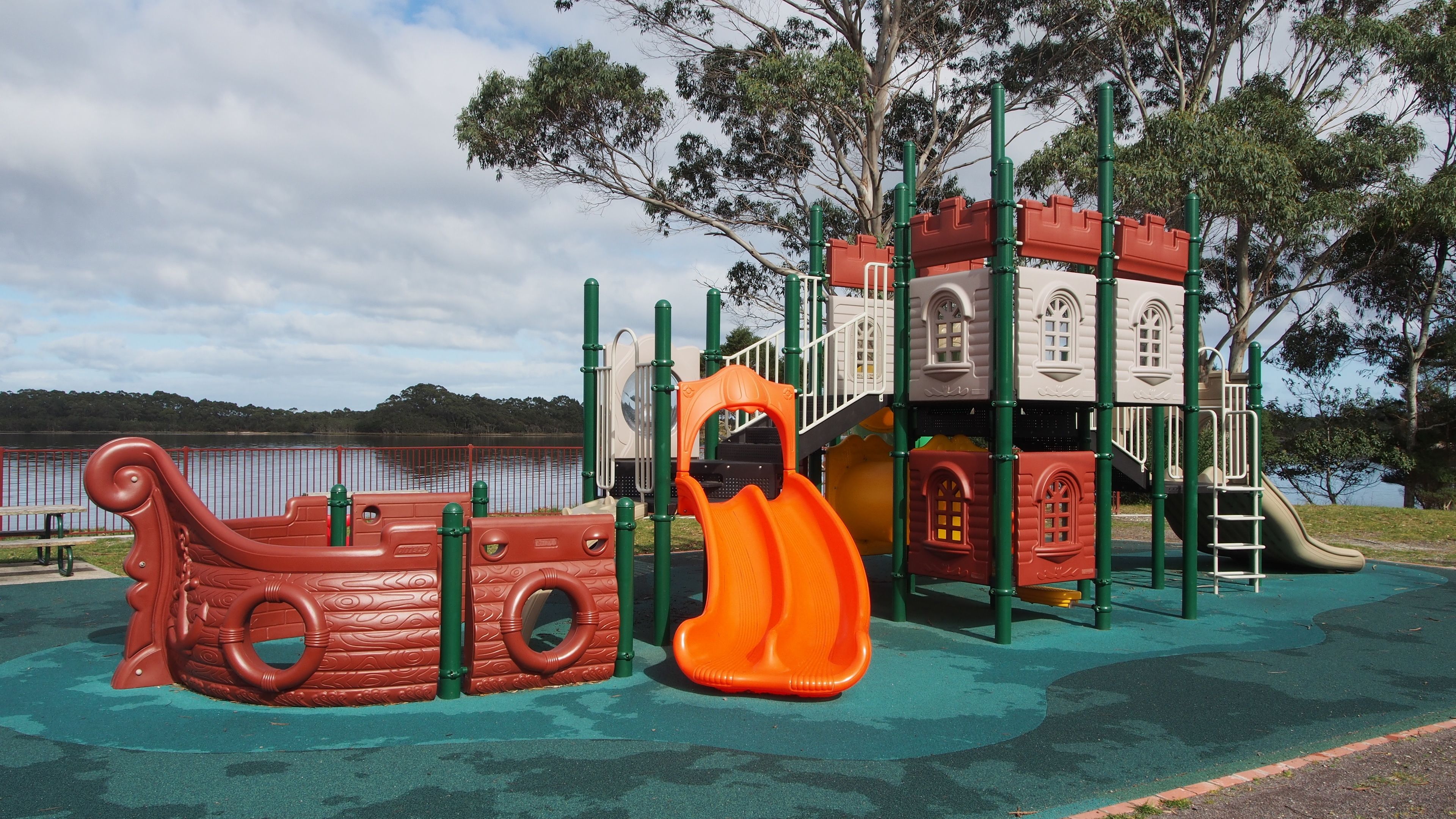 A playground with a slide, climbing structures, and a ship-themed play area.