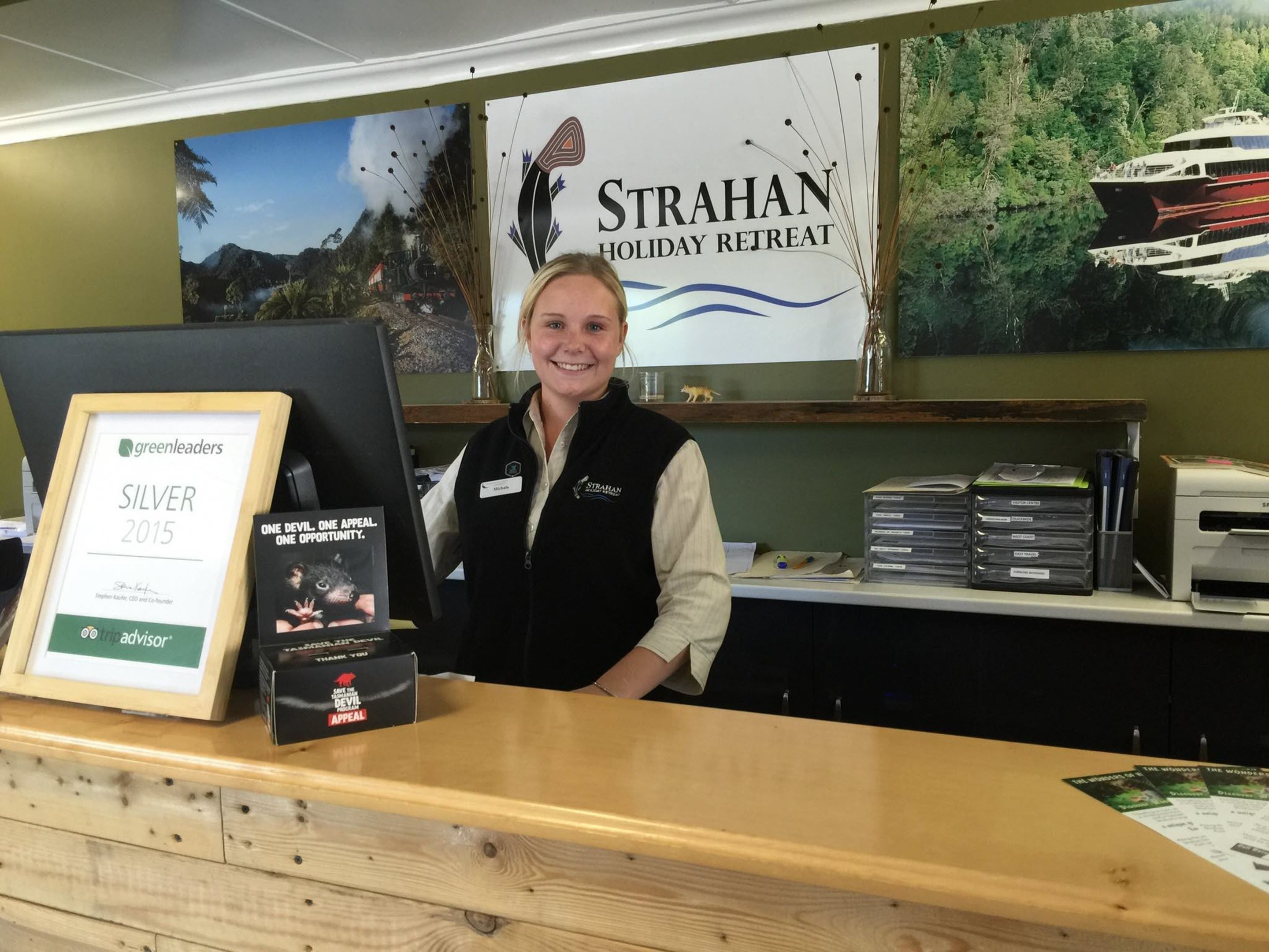 A reception desk with a framed award, a computer, and a banner for Strahan Holiday Retreat.