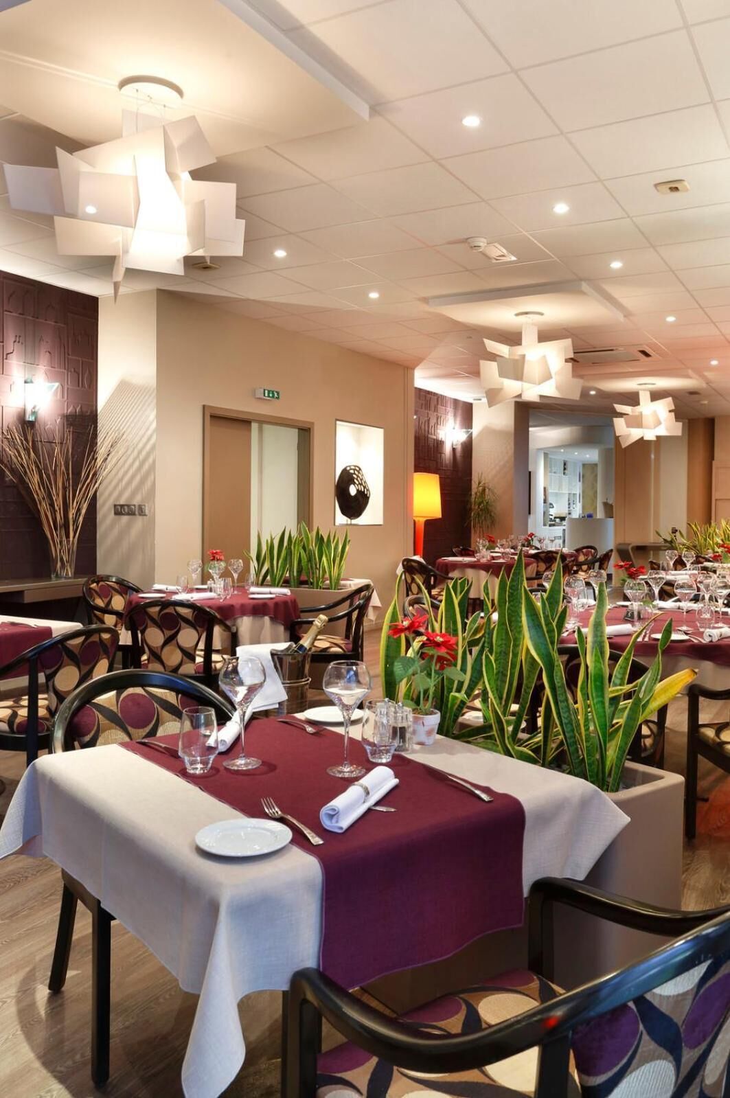 Una sala ristorante con tavoli apparecchiati, sedie e un soffitto con illuminazione a incasso.