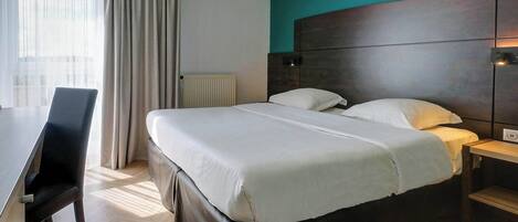 Una habitación de hotel con una cama, un escritorio y una silla.
