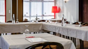 A restaurant with tables set for dining, featuring white tablecloths and wine glasses.