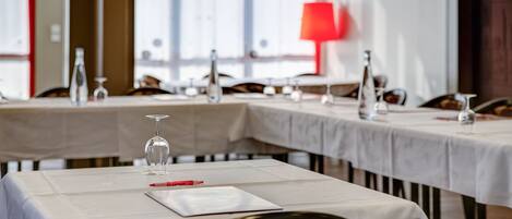 A restaurant with tables set for dining, featuring white tablecloths and wine glasses.