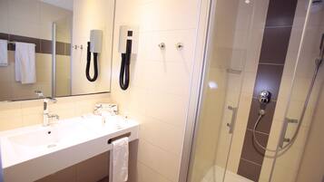 Un baño moderno con lavamanos, espejo y ducha.