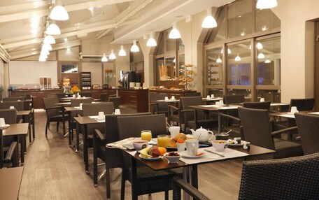 A spacious dining area with multiple tables and chairs, a buffet setup, and a kitchen in the background.