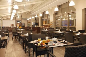 A spacious dining area with multiple tables and chairs, a buffet setup, and a kitchen in the background.