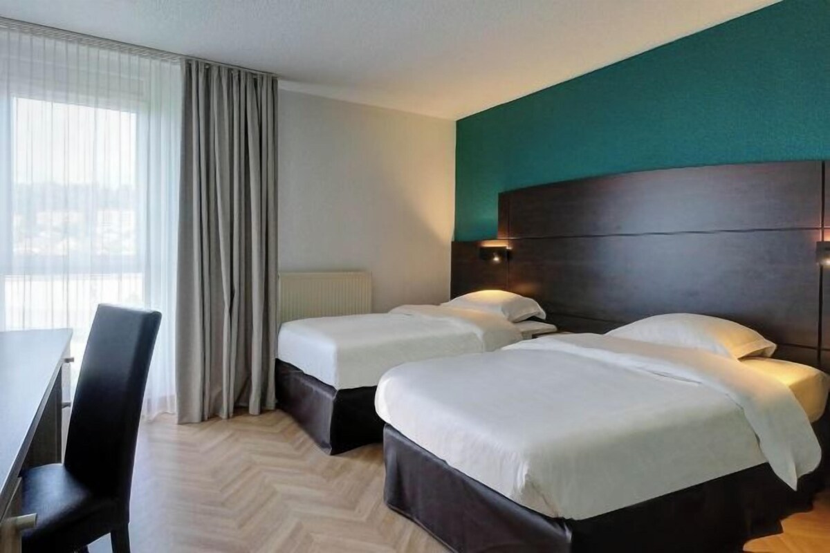 Habitación de hotel con dos camas, un escritorio y una silla.