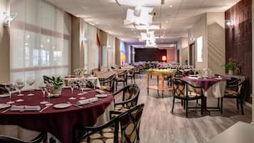 Un vaste espace dédié à la salle à manger, avec des tables rondes, des chaises et une scène en arrière-plan.