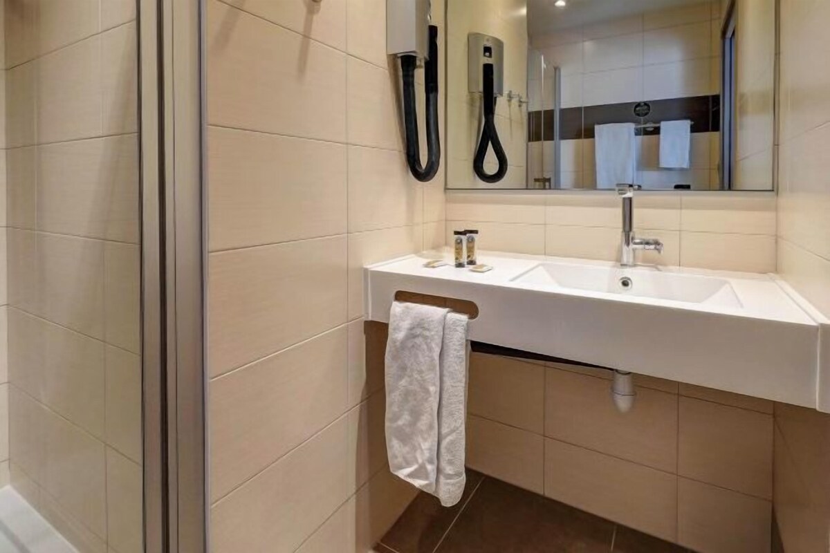 Une salle de bain moderne avec un lavabo blanc, un miroir et un porte-serviettes.