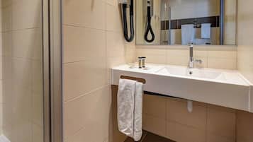 A modern bathroom with a white sink, a towel rack, and a handheld showerhead.