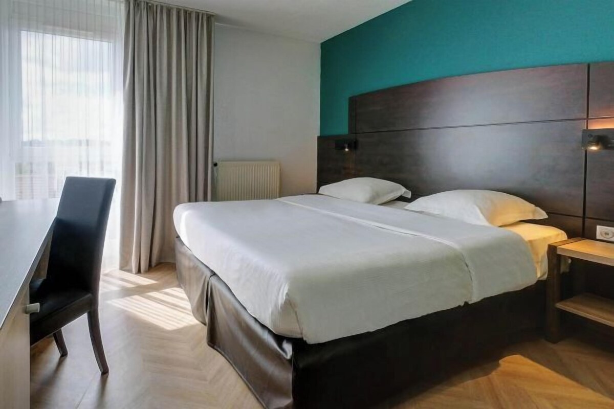 Une chambre d’hôtel avec un grand lit, un bureau et une vue sur la ville.