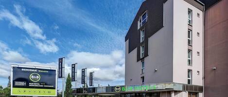 A B&B hotel with a modern design, a covered entrance, and a parking area.