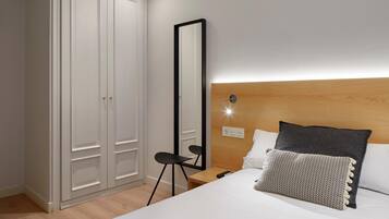 A bedroom with a bed, a nightstand, a mirror, and a wardrobe.
