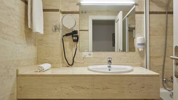 Un baño con lavabo, espejo, toallero, secador de pelo y ducha.