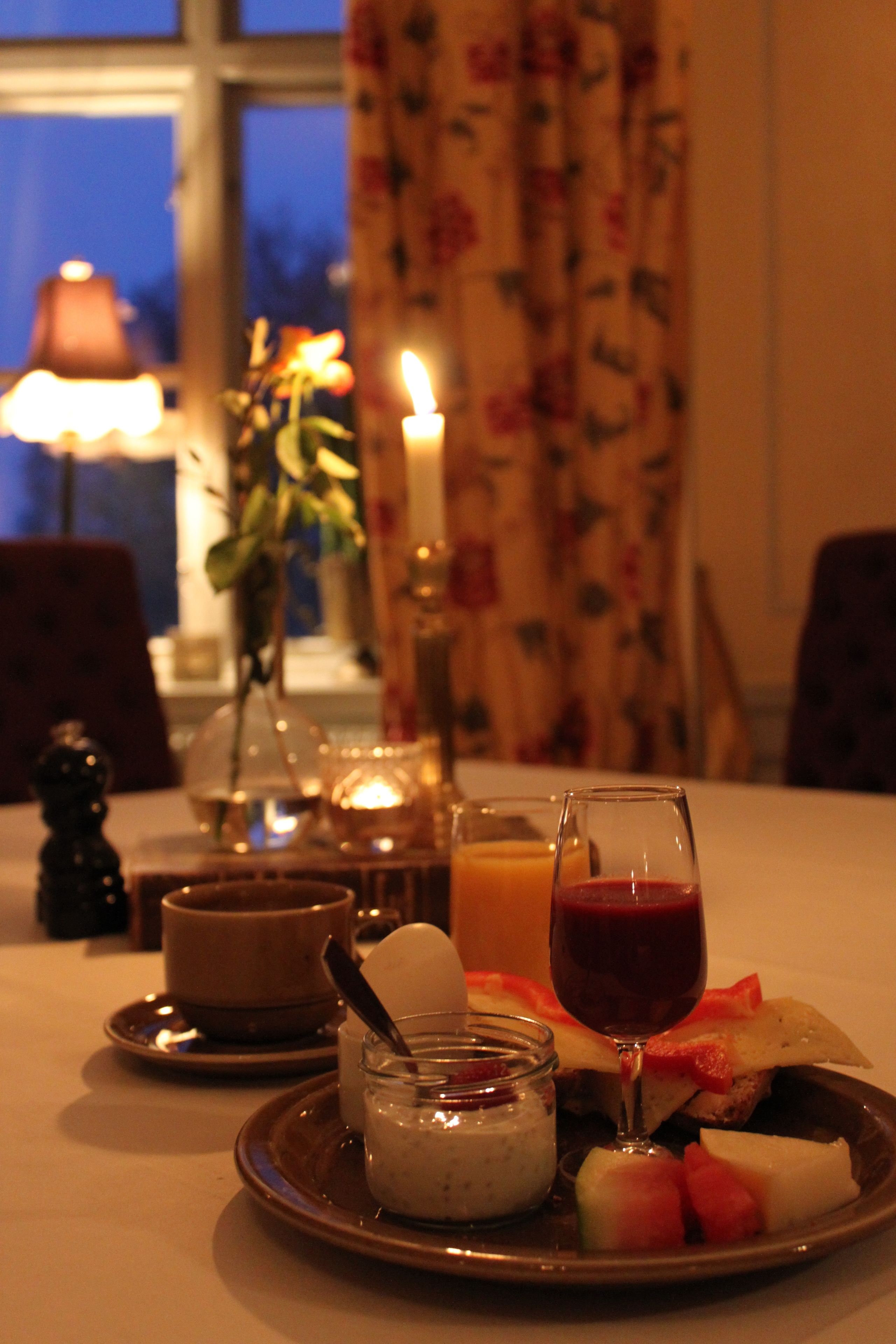 A dining table with a plate of food, a glass of red wine, and a candle.