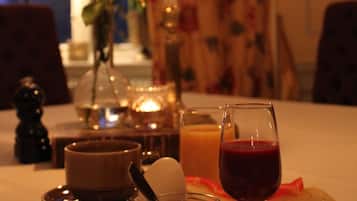 A dining table with a plate of food, a glass of red wine, and a candle.