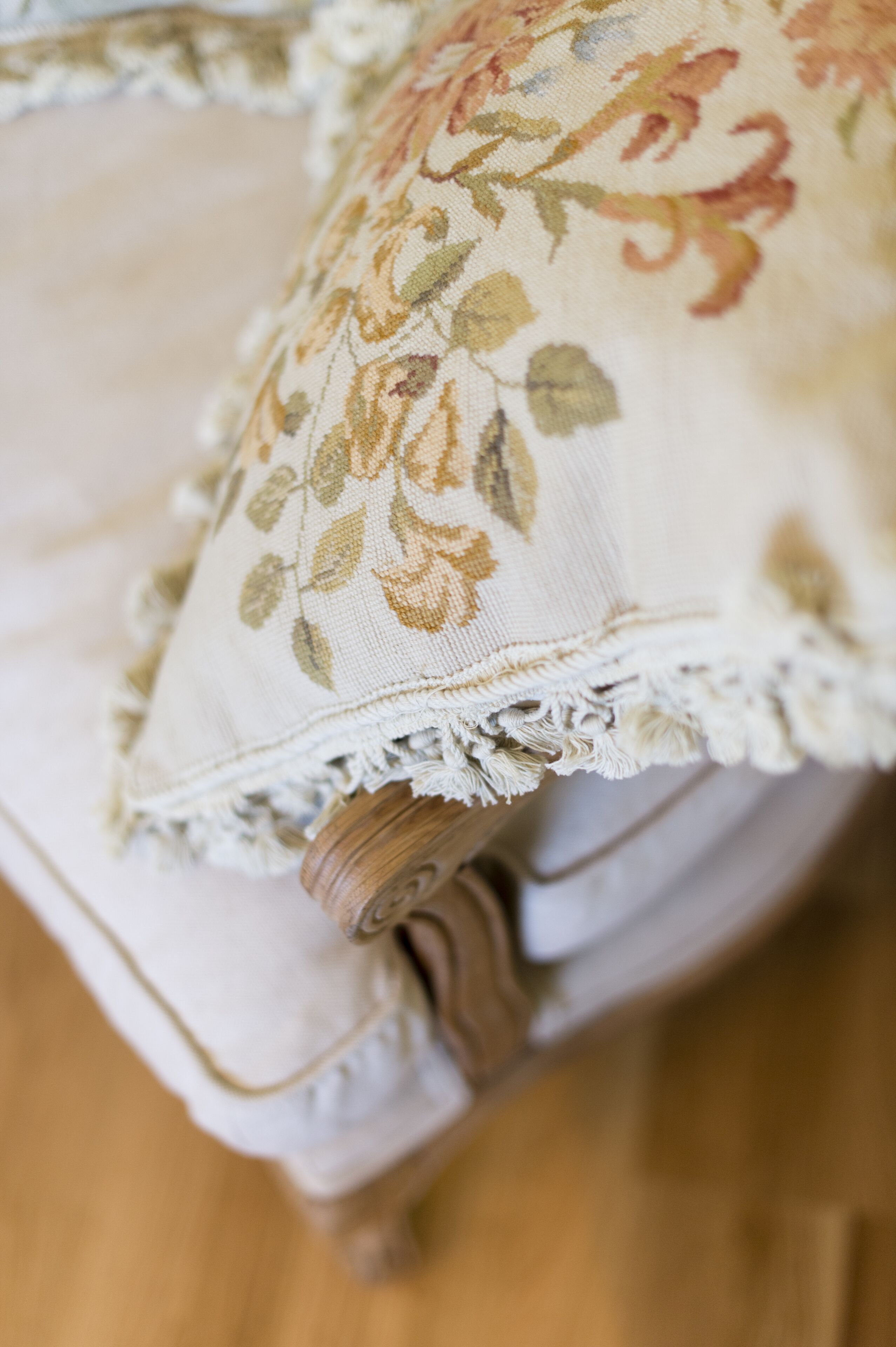 A close-up of a cushion with a floral pattern and a frayed edge.