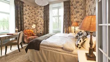 A bedroom with a bed, a chair, a desk, and two lamps.