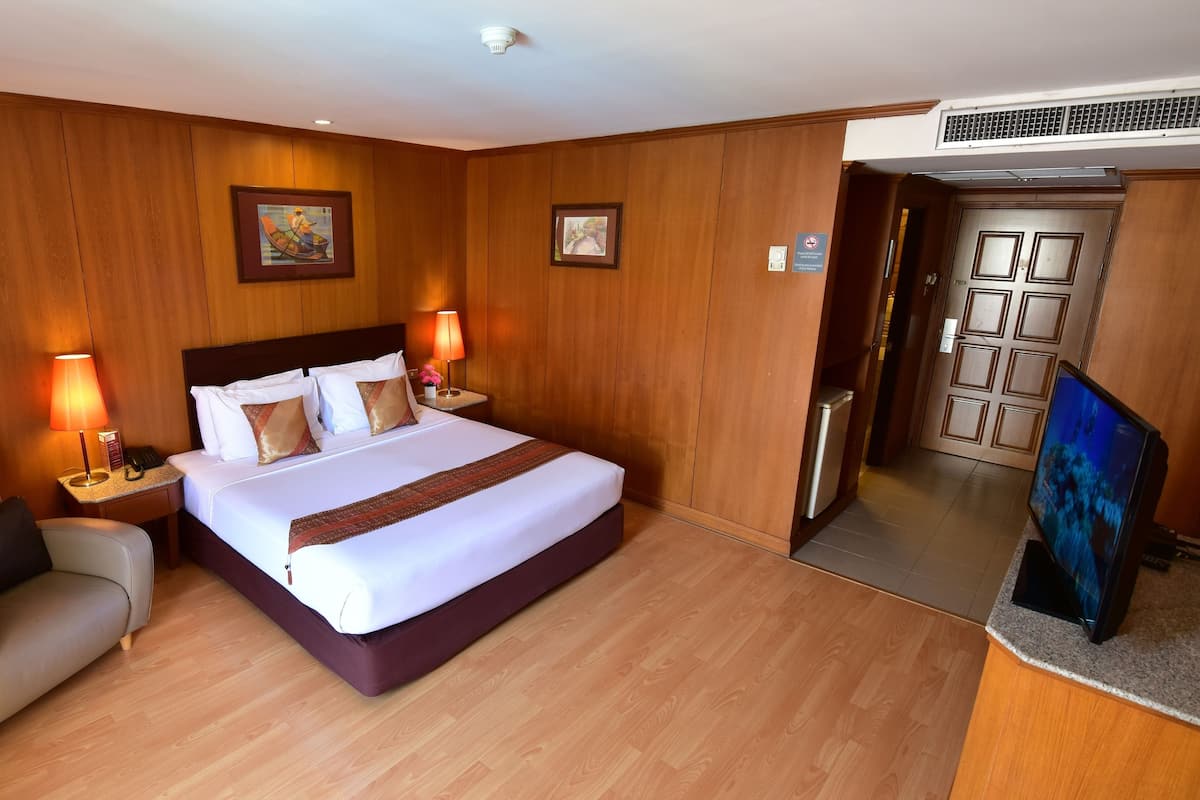 Une chambre d’hôtel avec un grand lit, un bureau équipé d’un ordinateur, une chaise et un téléviseur.