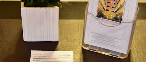 A registration card, a business card, and a flower arrangement on a table.