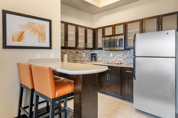 Una cocina moderna con armarios de madera oscura, un refrigerador de acero inoxidable, un microondas y un salpicadero de azulejos.