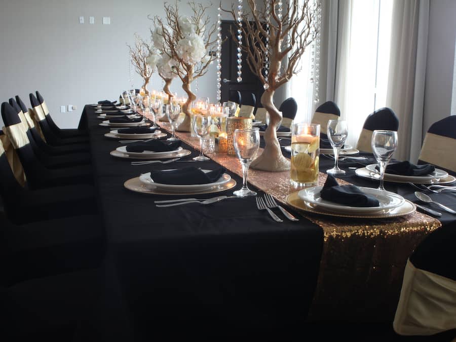 A long dining table set for a formal meal with multiple place settings, glasses, and a decorative centerpiece.