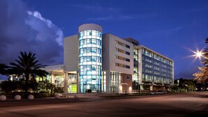 A modern hotel with a curved glass facade, multiple floors, and a well-lit entrance. - Staybridge Suites St. Petersburg Downtown by IHG (St. Petersburg)