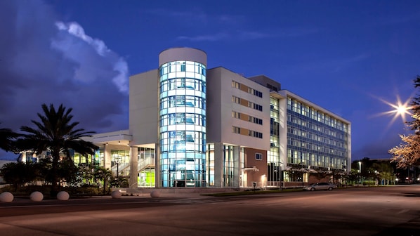 A modern hotel with a curved glass facade, multiple floors, and a well-lit entrance. - Staybridge Suites St. Petersburg Downtown by IHG (St. Petersburg)